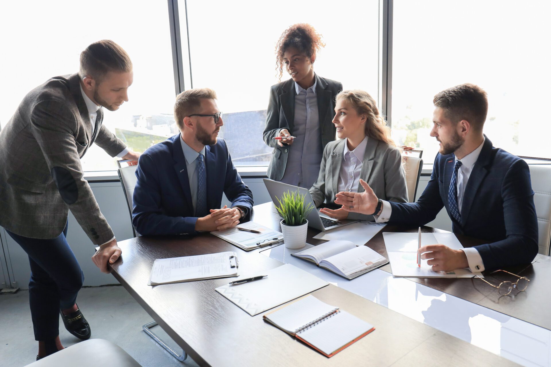 Group of young modern people in formalwear smiling and discussing something while working in the modern office Group of young modern people in formalwear smiling and discussing something while working in the modern office.