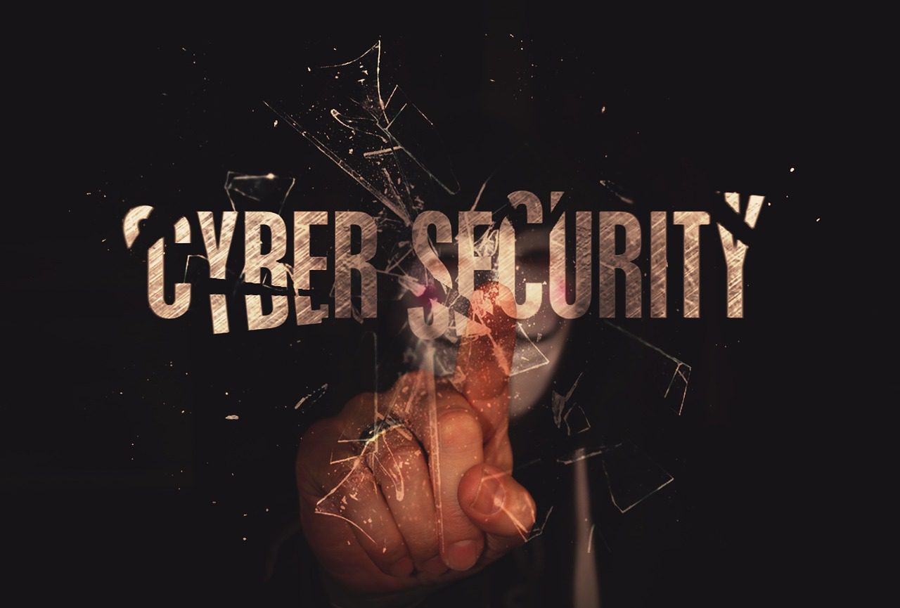 A finger touching a breaking "Cybersecurity" text to symbolize digital vulnerabilities.